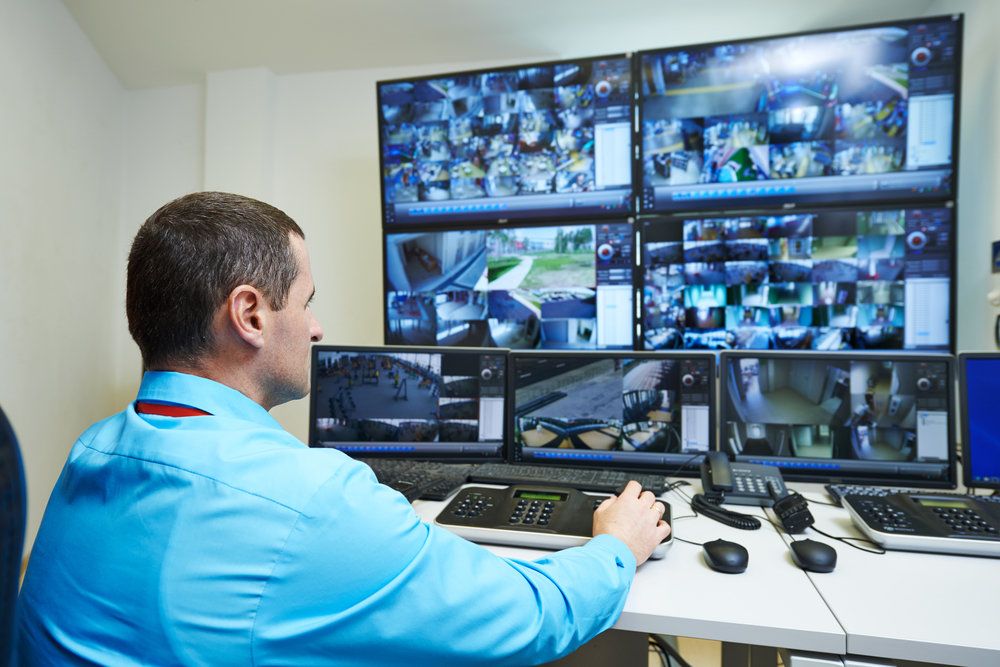 A man viewing several security monitors